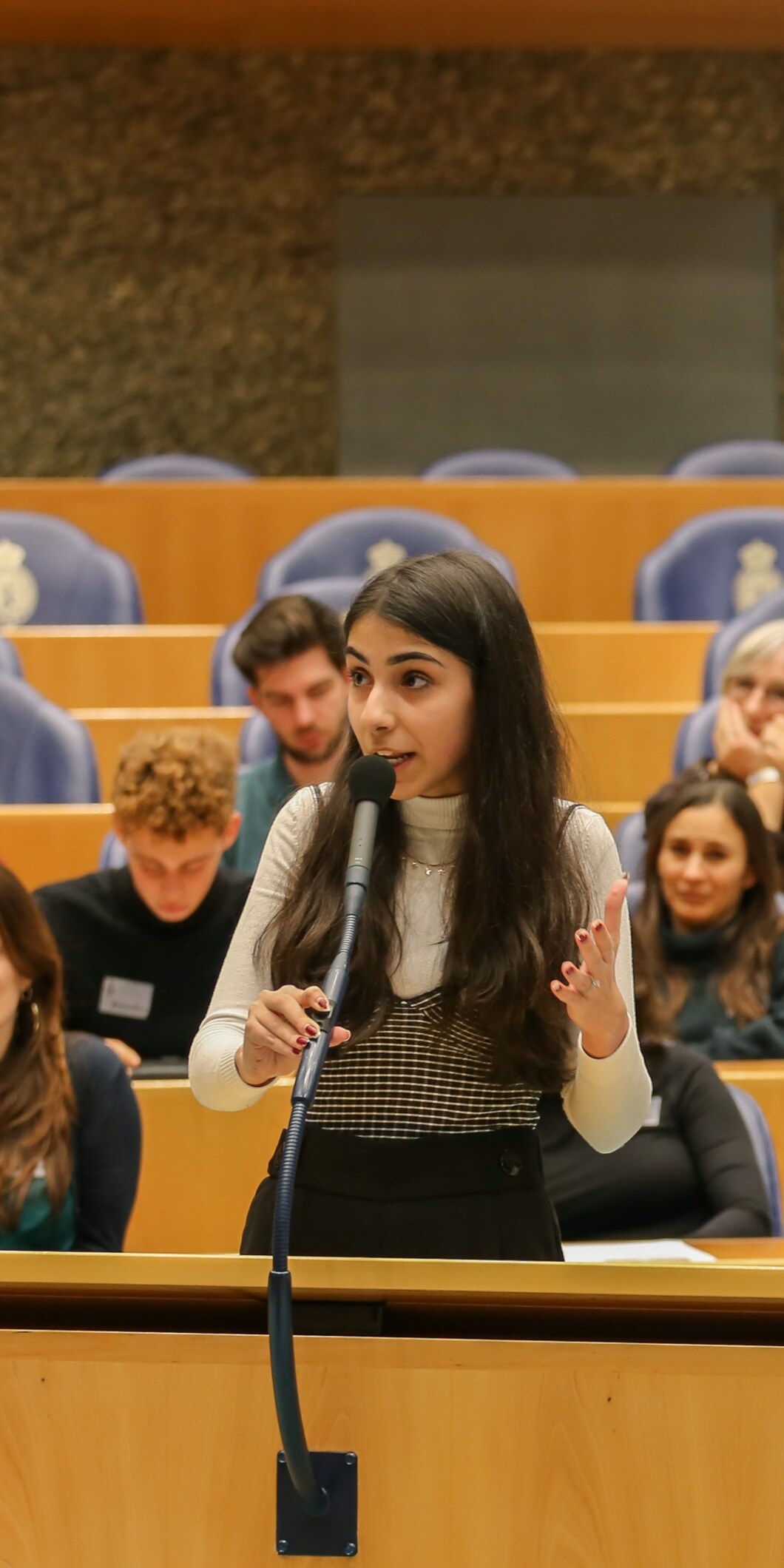 Een jonge vrouw staat achter de interruptiemicrofoon van de Tweede Kamer