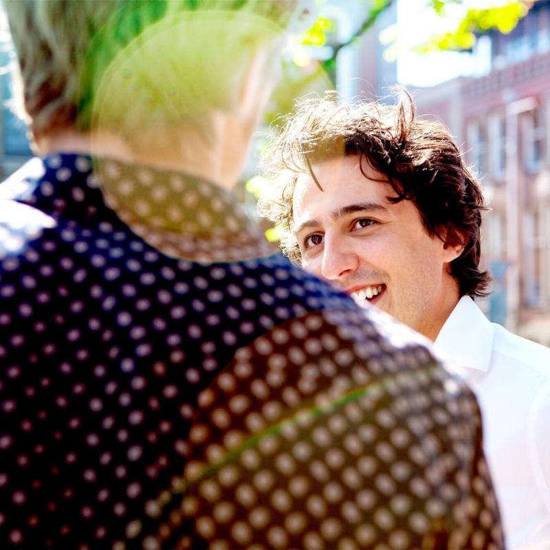 Jesse Klaver lachend naar een persoon waarvan wij alleen de rug zien.